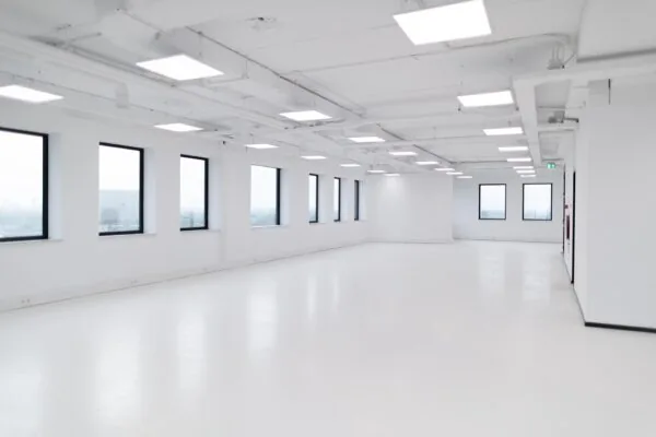 Lichte, lege kantoorruimte in het Rivium Quadrant met grote ramen en plafondverlichting.